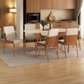 Conjunto de jantar Manila com mesa retangular off white e 6 cadeiras estofadas, ambientado com tapete e vaso de planta